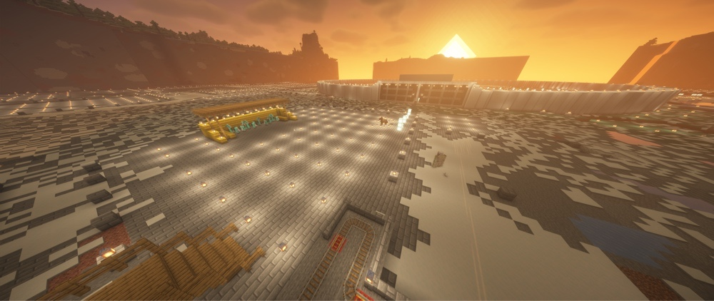 Ein Minecraft-Screenshot im stimmungsvollen Sonnenuntergang. Man sieht eine gigantische Baustelle mit den ersten geschwungenen, weißen Grundmauern von Minas Tirith auf einer großen, beleuchteten Steinfläche. Vorne links steht ein hölzernes Baugerüst.