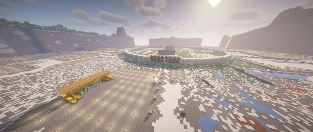 Ein Minecraft-Screenshot bei Tageslicht. Die kreisförmige, weiße Stadtmauer von Minas Tirith ist im Bau und rahmt eine große Innenfläche ein. Im Hintergrund ragen massive, teils noch im Bau befindliche Berge in den Himmel.