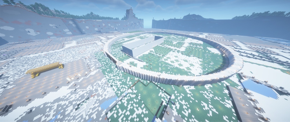 Ein leicht erhöhter Minecraft-Screenshot, der die gewaltigen Ausmaße der Baustelle zeigt. Der geschlossene weiße Mauerring von Minas Tirith sticht deutlich hervor. Im Zentrum der Anlage befindet sich ein großer, rechteckiger Rohbau, umgeben von schneebedecktem und begrüntem Boden.